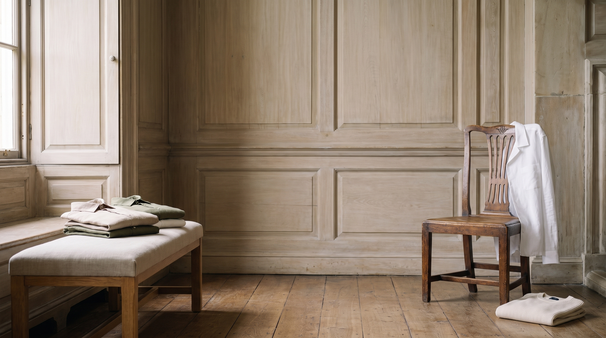 Folded linen shirts on a bench beside a window
