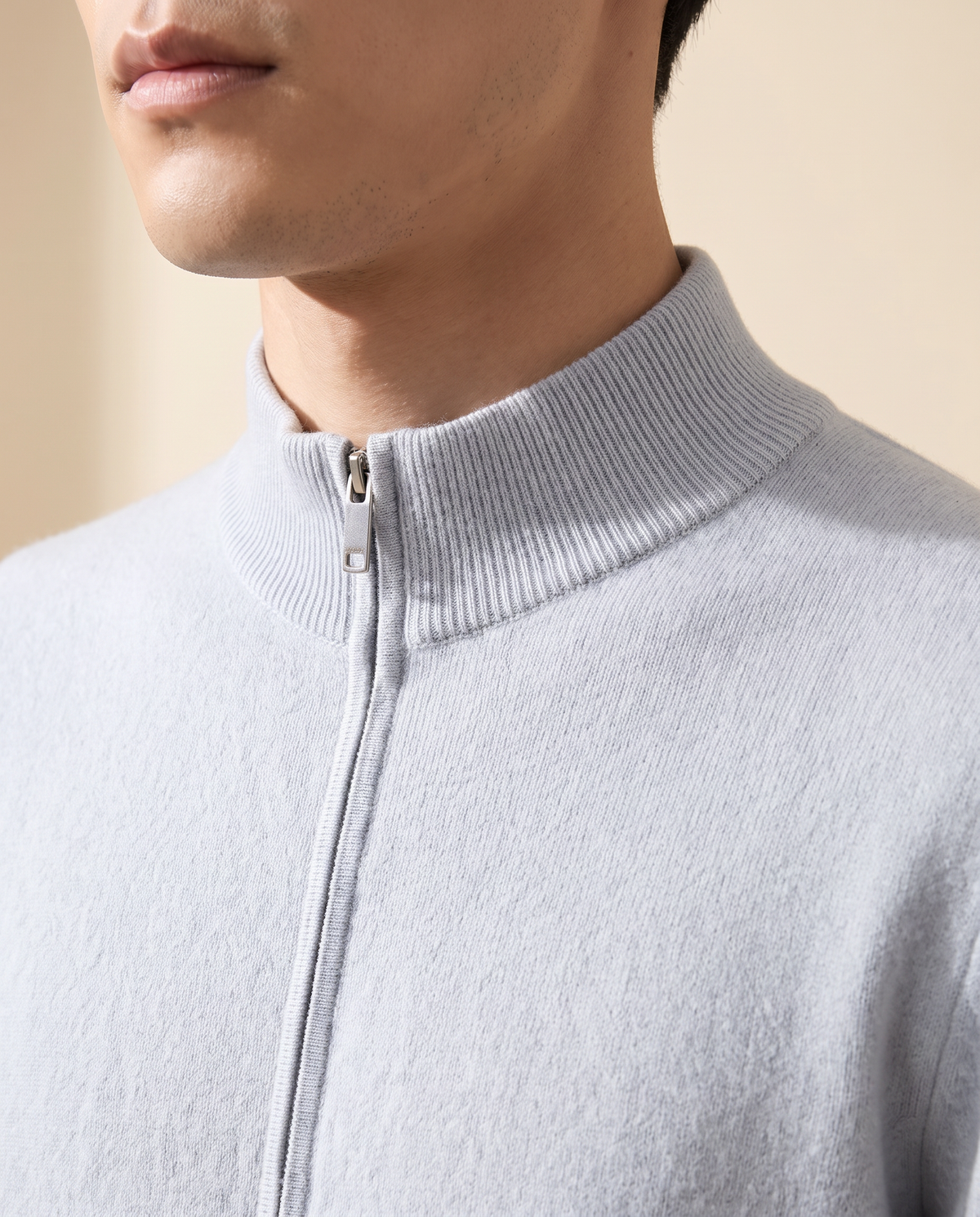 Close-up of the ribbed stand collar and zip pull on the light blue merino cardigan