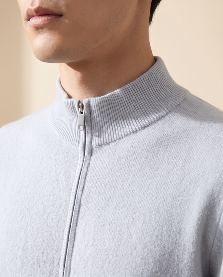 Close-up of the ribbed stand collar and zip pull on the light blue merino cardigan
