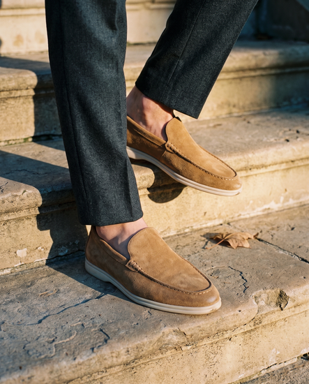 Suede loafers worn on sunlit stone steps