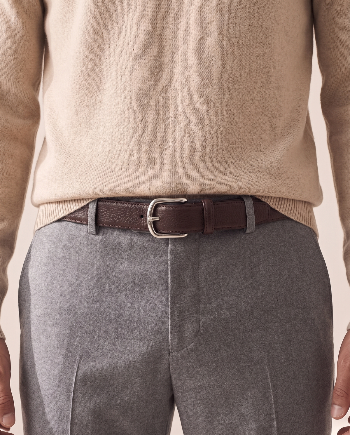The Chester leather belt worn through the loops of plain grey trousers