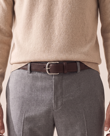 The Chester leather belt worn through the loops of plain grey trousers