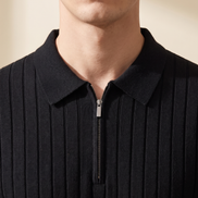 The Osborne ribbed zip polo in black, close-up of folded collar and silver zip
