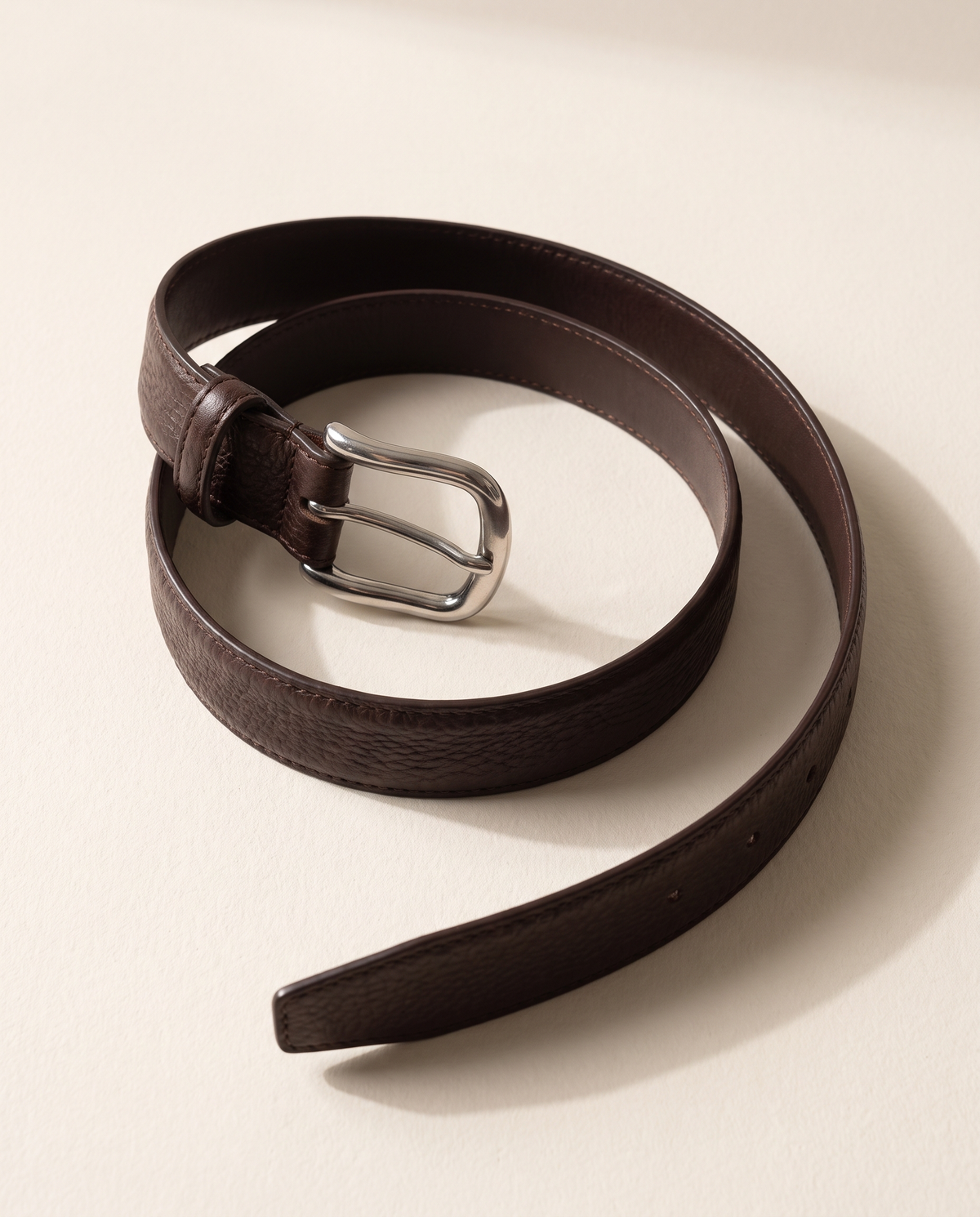 The Chester leather belt laid in an open curve