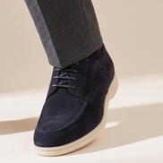 Close-up of The Regent worn, low three-quarter on the suede vamp, lacing and cream sole at the trouser break